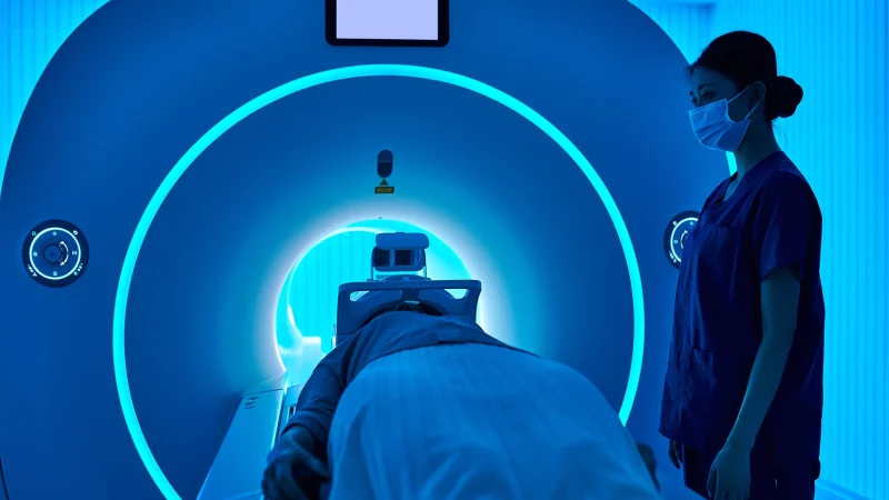 Side view of one asian female nurse operating MRI scan machine in the MRI-scanner room.